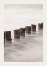 Fotografia di pali di legno in linea retta circondati dalla superficie nebbiosa del mare-3