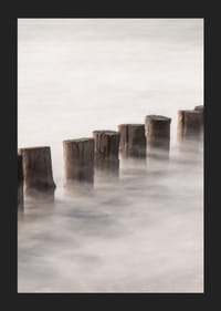 Fotografia di pali di legno in linea retta circondati dalla superficie nebbiosa del mare-5