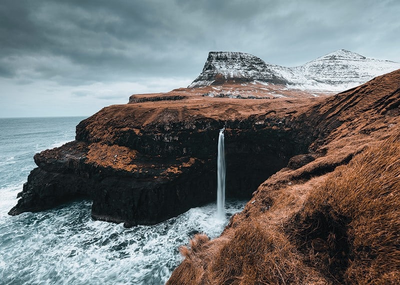 Fotografische Landschaft mit hohem Wasserfall an karger Küste-12