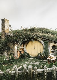 Trawiasty domek hobbita z żółtymi okrągłymi drzwiami i ogrodem kwiatowym-7
