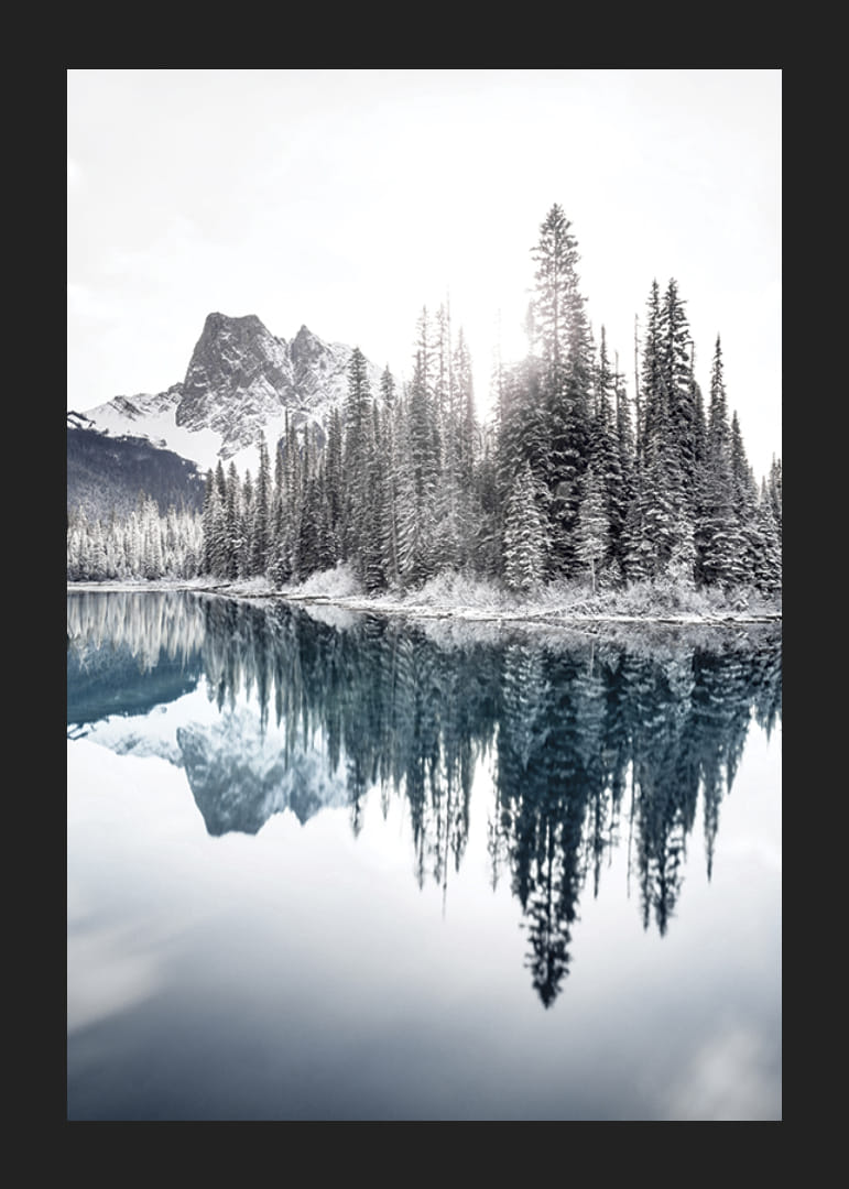 Valokuva lumipeitteisistä kuusista kirkkaan sinisen järven ja vuorten rannalla-12