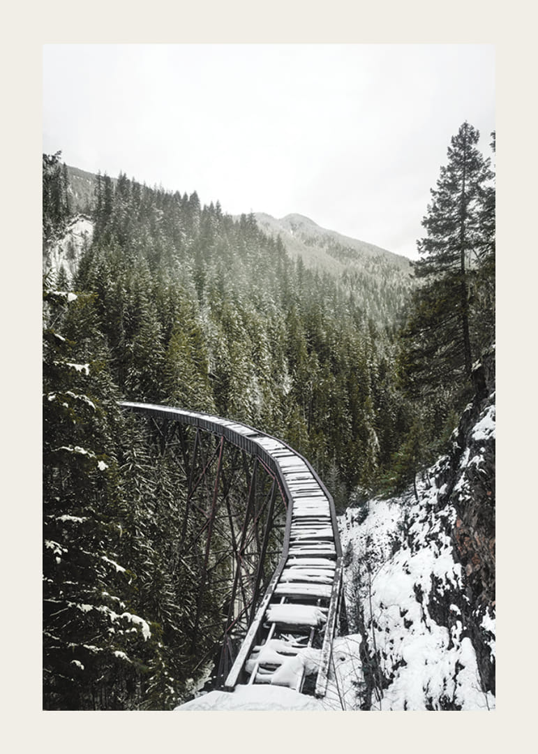 Fénykép egy hófödte vasúti hídról lucfenyőerdő felett téli tájban-12