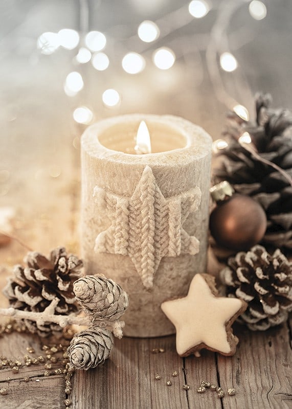 Bougie allumée avec une décoration en étoile tricotée parmi des pommes de pin et des boules de Noël-12