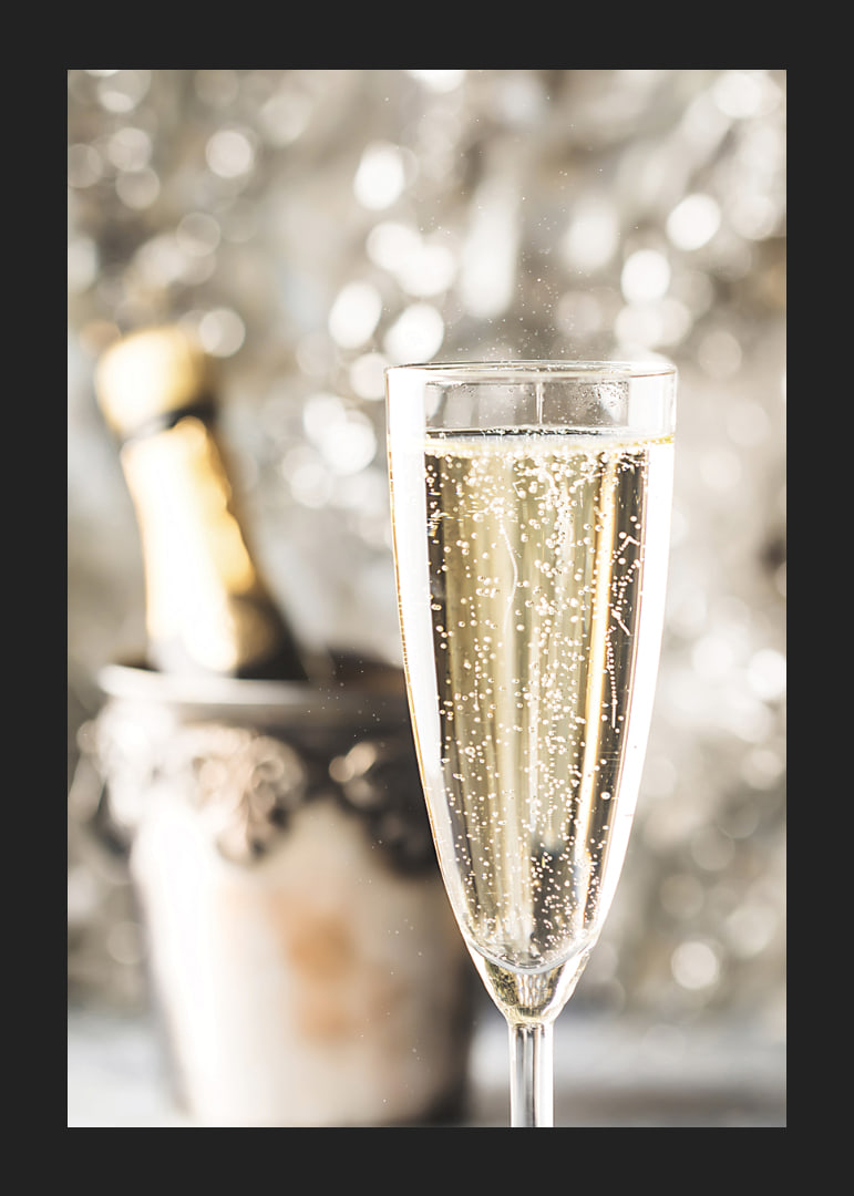Fotografiskt närbild av champagneglas med bubblor och suddig flaska i bakgrunden-12