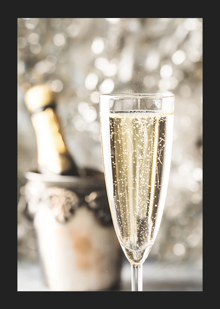Photographic close-up of champagne glass with bubbles and blurred bottle in the background-12