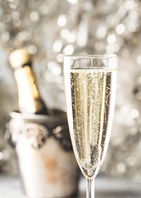 Fotografiskt närbild av champagneglas med bubblor och suddig flaska i bakgrunden-7