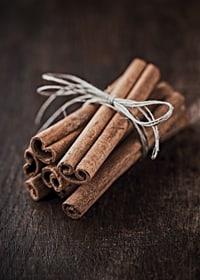 Close-up of cinnamon sticks in a bundle on dark wooden table-7