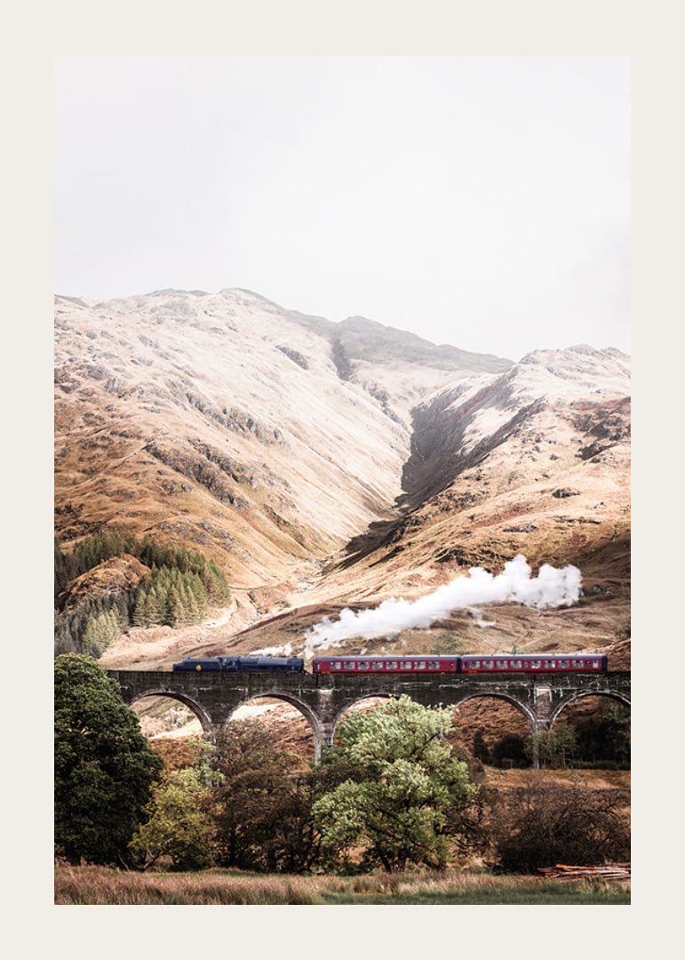 Steam train on stone viaduct in front of bright mountains in autumn landscape-12