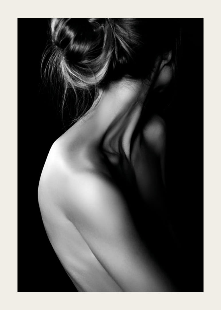 Fekete-fehér fénykép egy feltűzött hajjal és fedetlen háttal rendelkező nőről-12