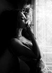 Black and white photograph of woman smoking by a window-7