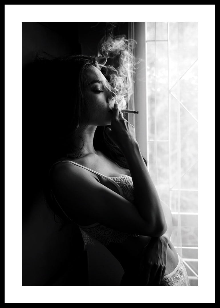Black and white photograph of woman smoking by a window-12
