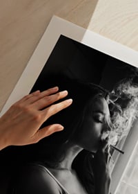 Black and white photograph of woman smoking by a window-9