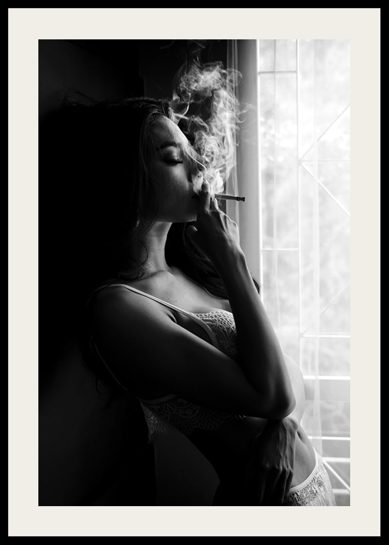 Black and white photograph of woman smoking by a window-12