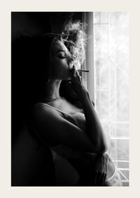 Photographie en noir et blanc d'une femme fumant près d'une fenêtre-3