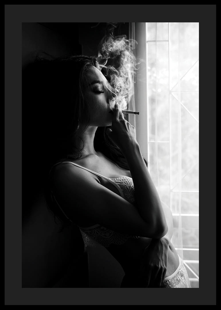 Photographie en noir et blanc d'une femme fumant près d'une fenêtre-12