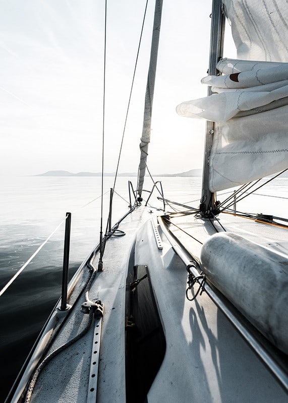 Photograph of sailboat deck with white sails and calm sea-12