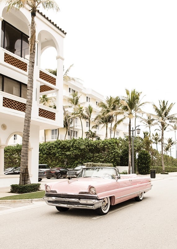 Photographic vintage car in pink in front of palm-lined buildings-12