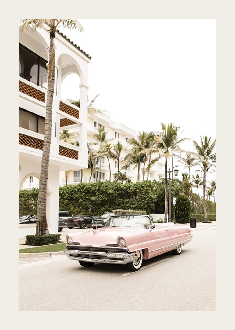 Photographic vintage car in pink in front of palm-lined buildings-12