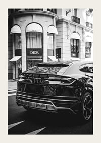 Svartvit Lamborghini SUV framför Dior-butik i stadsmiljö-3