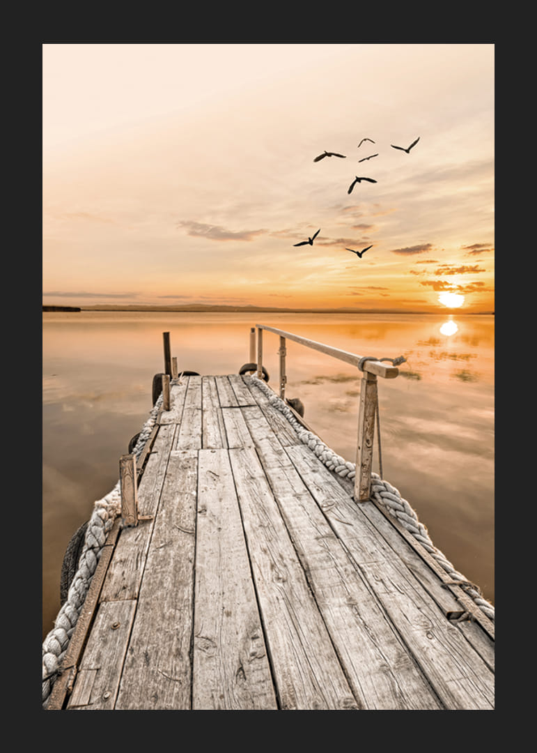 Fotografía de un antiguo muelle de madera junto a aguas tranquilas al atardecer.-12