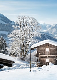 Photograph of wooden cabin in snow-covered mountain landscape and blue sky-7