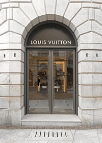 Store entrance with Louis Vuitton sign in stone facade, brown tones-7