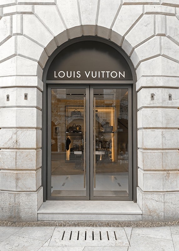 Store entrance with Louis Vuitton sign in stone facade, brown tones-12