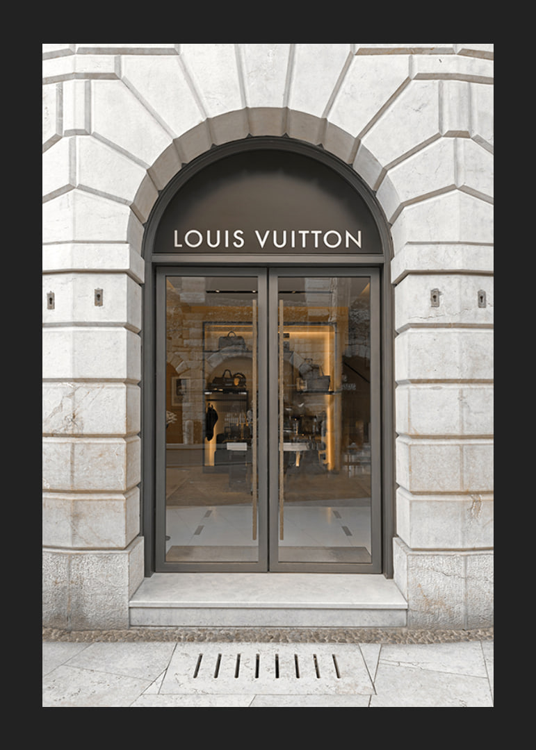 Store entrance with Louis Vuitton sign in stone facade, brown tones-12