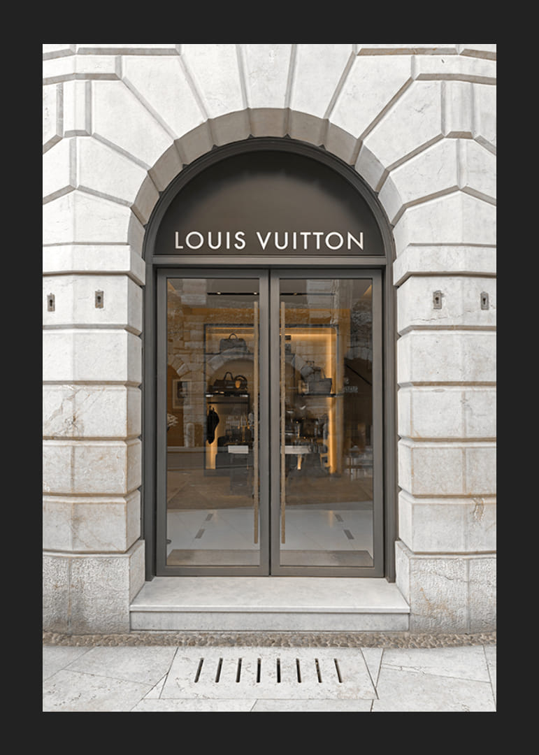 Store entrance with Louis Vuitton sign in stone facade, brown tones-12