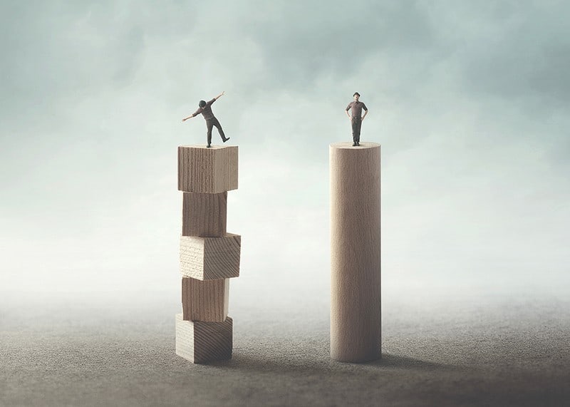 Two people balancing on wooden pillars against gray background-12