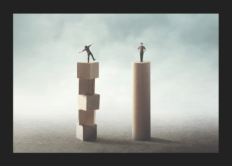 Kaksi ihmistä tasapainoilee puisilla pylväillä harmaata taustaa vasten-12