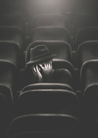 Illustrated man with hat hiding his face in dark cinema hall-7