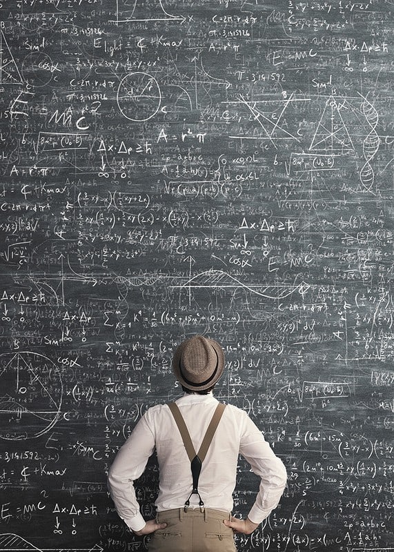 Muž v klobúku stojaci pred veľkou tabuľou s matematickými vzorcami-12