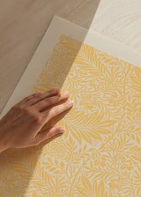 Tätt och grafiskt mönster med stiliserade larkspurblommor och små blad i gult, beige och blå toner mot ljus bakgrund-3