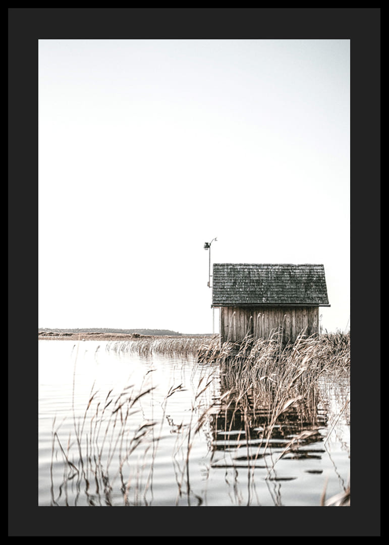 Motivo fotográfico de una cabaña de madera junto a los juncos y un lago tranquilo.-12