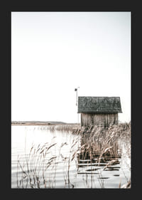 Motivo fotográfico de una cabaña de madera junto a los juncos y un lago tranquilo.-5