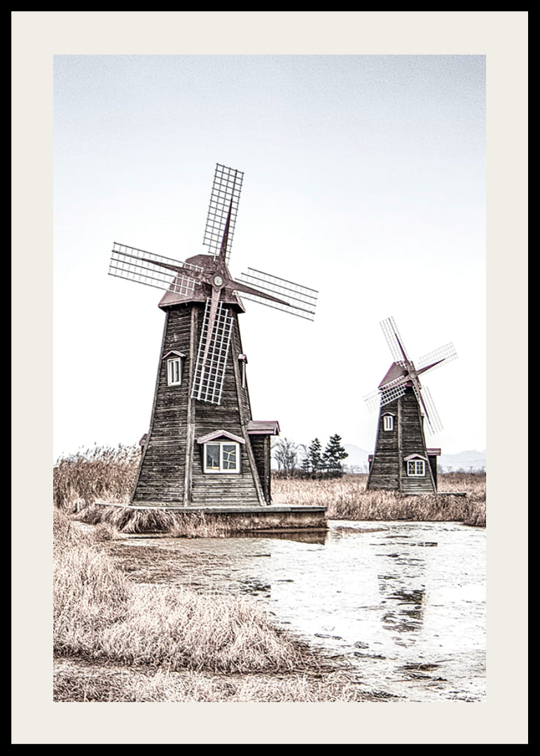 Valokuva kahdesta vanhasta puisesta tuulimyllystä ruo'on ja veden äärellä-12