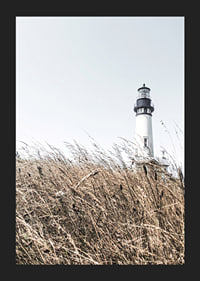 Fotografía de un faro blanco detrás de un césped alto de color beige contra un cielo brillante.-5