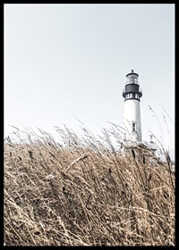 Fotografía de un faro blanco detrás de un césped alto de color beige contra un cielo brillante.-6