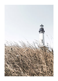 Fotografía de un faro blanco detrás de un césped alto de color beige contra un cielo brillante.-1