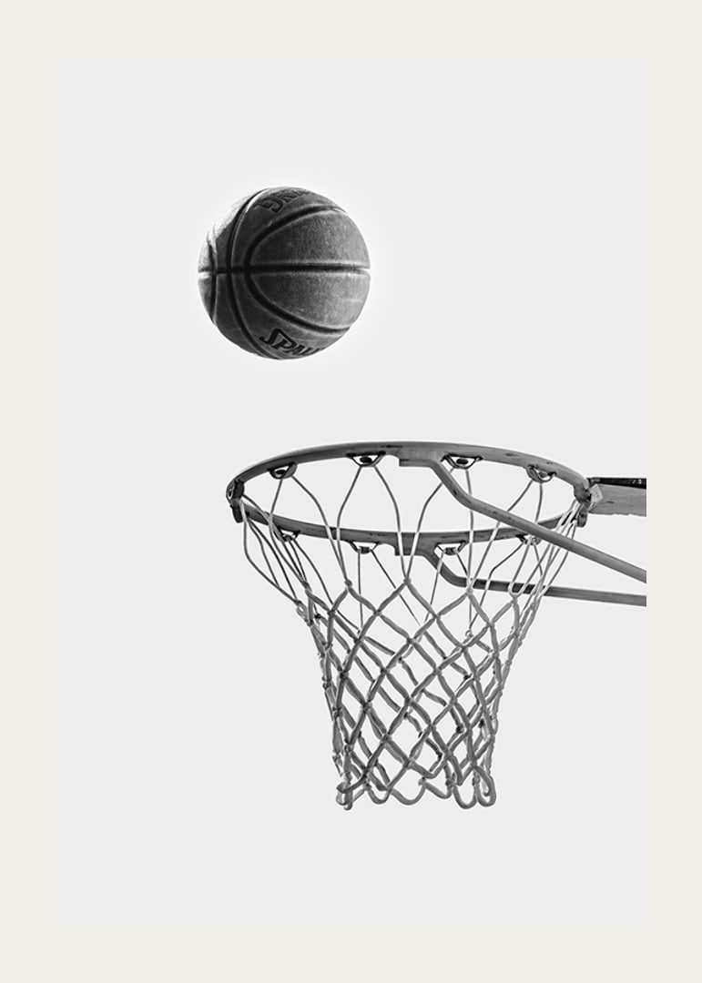 Black and white photo of basketball above basket against light background-12