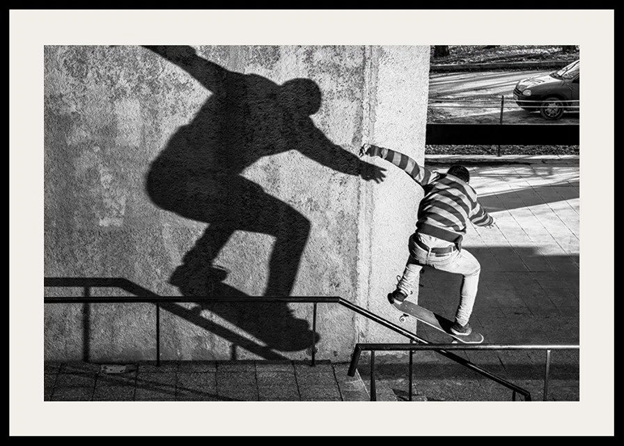 Black and white photo of skateboarder climbing railing outdoors-12