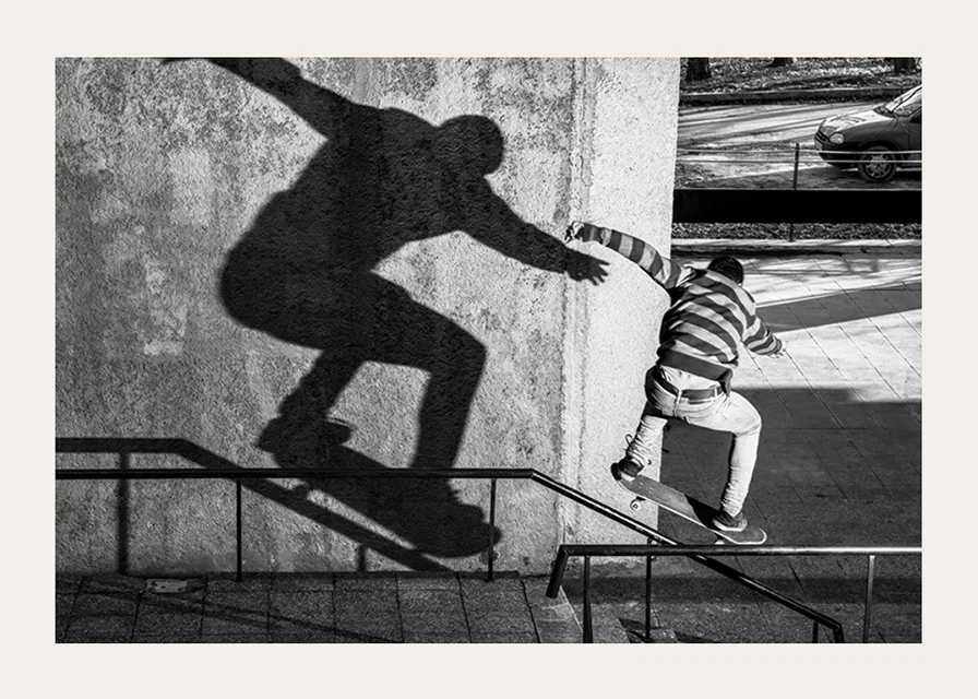 Black and white photo of skateboarder climbing railing outdoors-12