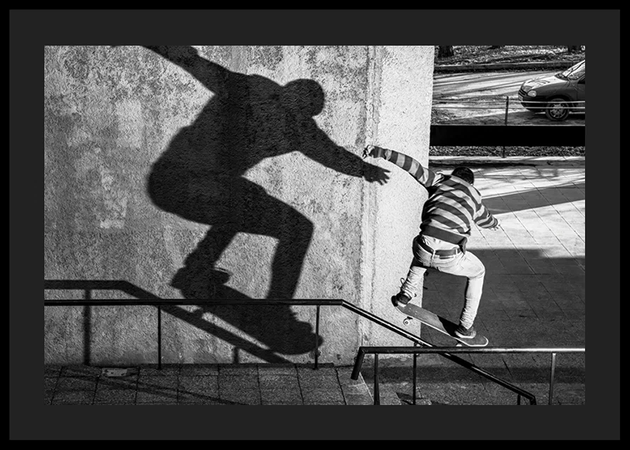 Black and white photo of skateboarder climbing railing outdoors-12