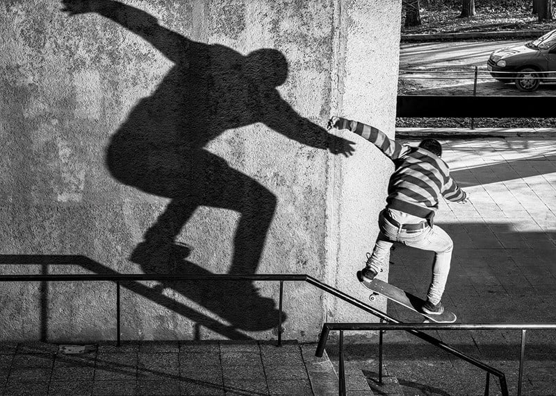 Foto em preto e branco de skatista escalando corrimão ao ar livre-12