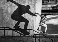 Black and white photo of skateboarder climbing railing outdoors-7