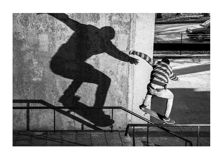 Black and white photo of skateboarder climbing railing outdoors-12