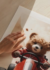 Illustrated teddy bear in red toy car on the road at speed-9