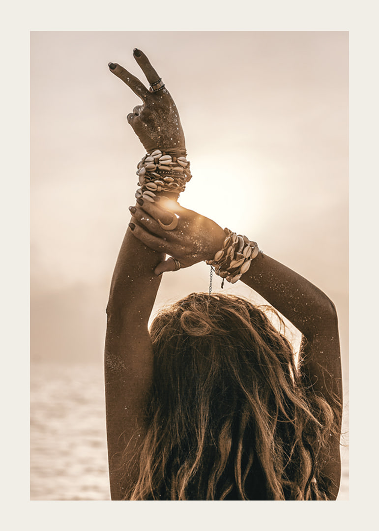 Woman with arms in the air, shell bracelet and backlight by the sea-12