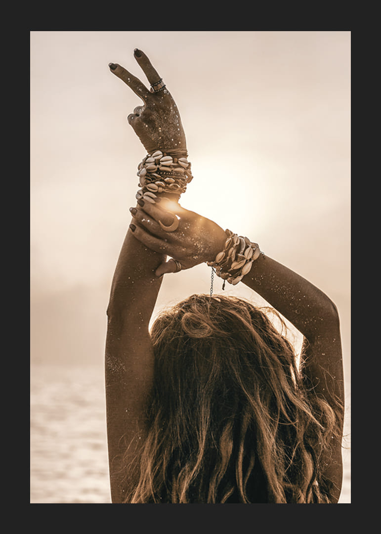 Nő a levegőbe emelt karokkal, kagylókarkötővel és háttérvilágítással a tengerparton-12